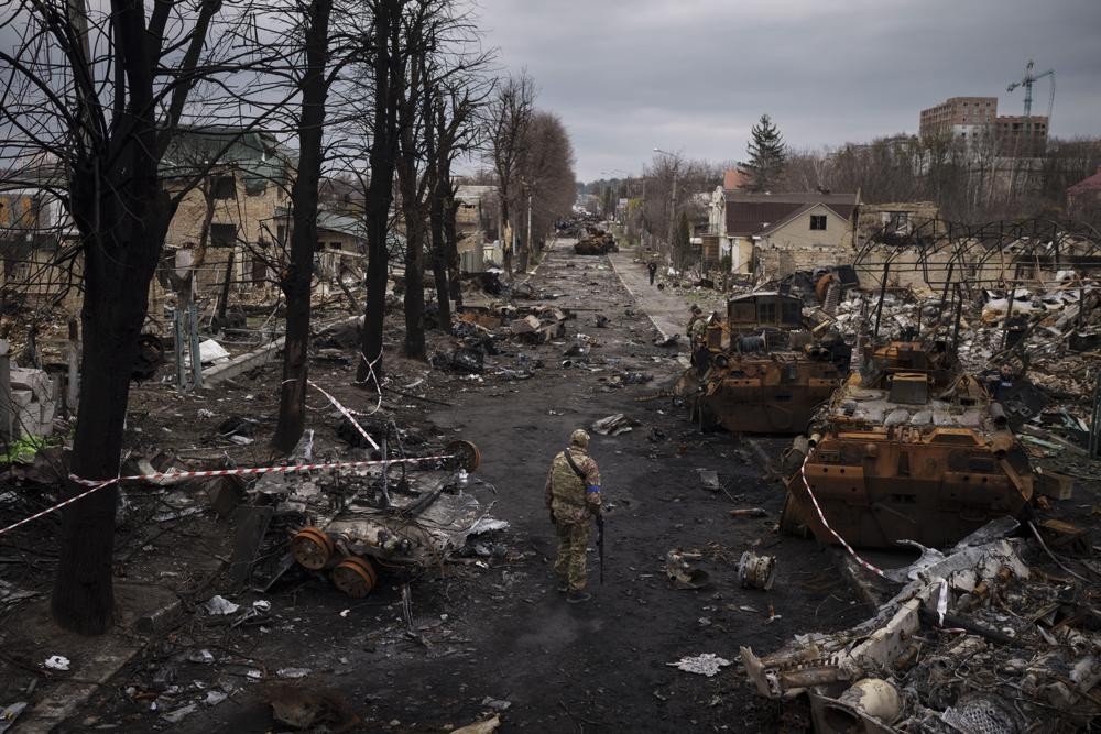 FILE - A Ukrainian serviceman walks amid destroyed Russian tanks in Bucha, on the outskirts of Kyiv, Ukraine, April 6, 2022. With Russian hopes for storming Kyiv and other major cities in northern Ukraine dashed by stiff resistance, Moscow has refocused its efforts on the country’s east, seeking to make gains there and use them to dictate its terms in talks on ending the conflict. (AP Photo/Felipe Dana, File)